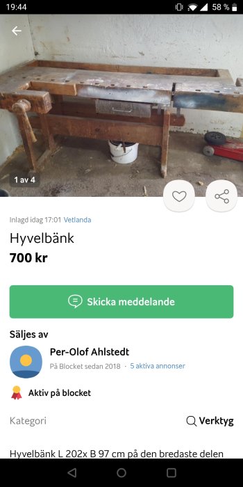 Använd hyvelbänk i trä med synlig slitage och metallbeslag, placerad i ett spartanskt utrymme.