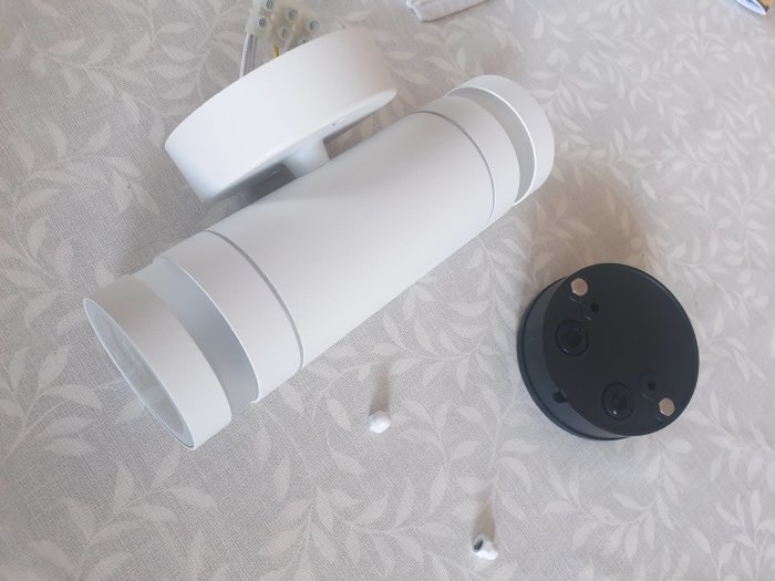 Vit Lyra 2 lampa med dubbla anslutningar demonterad på ett grått mönstrat tyg.