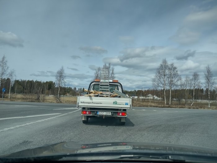 Hantverkares pickup lastad med material parkerad vid en korsning sedd från en bil.