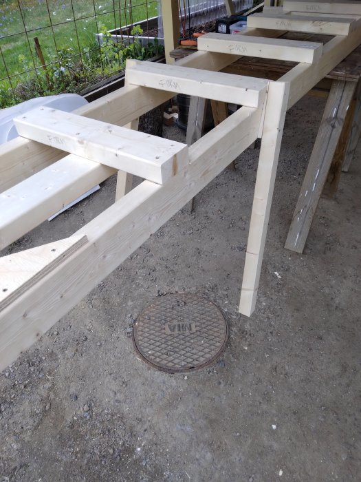 Nybyggd träbjälke strongback med stödben för stabiliserande av byggnadsmaterial på en byggarbetsplats.
