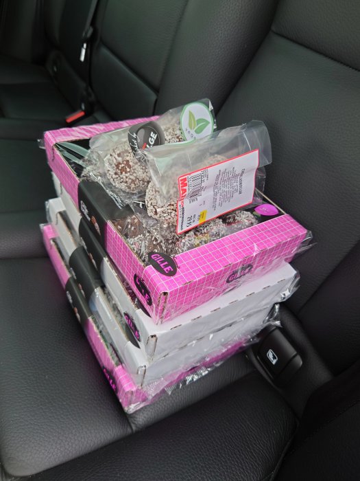 Flertal förpackningar med byggmaterial staplade på ett bilens baksäte.