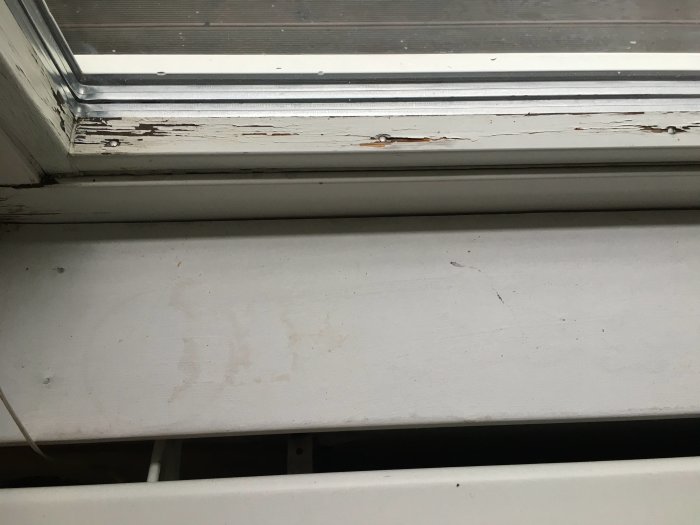 Fuktskadad trälist och fönsterbleck under fönster med vattenspår.