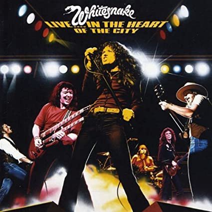 Omslaget till Whitesnake's livealbum "Live in the Heart of the City" med bandmedlemmar som uppträder på scen.