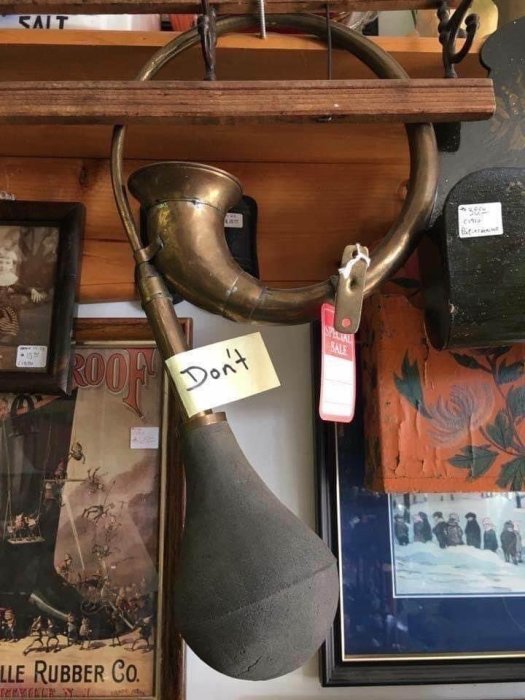 Antika föremål på vägg i en butik, inklusive ett gammalt horn och en boxningssäck med en lapp som säger "Don't".