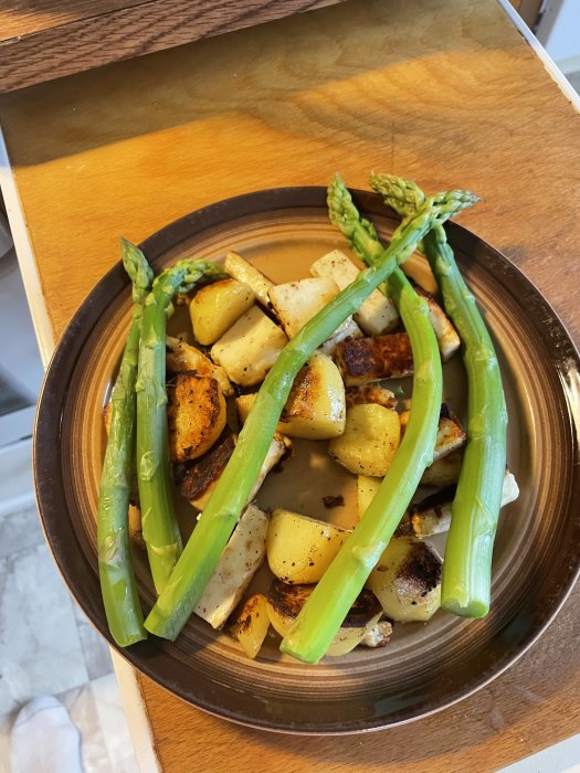 Tallrik med stekt sparris och potatis, hemodlad och nyskördad, använd i matlagning.