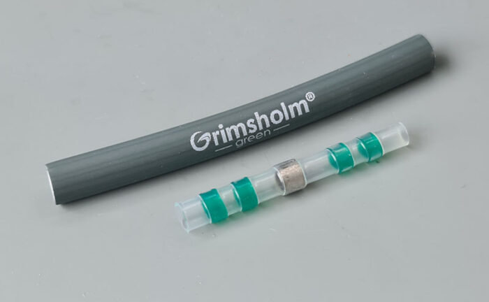 Lödskarvkoppling från Grimsholm med lödtenn och dubbla limtätningar, framför logotyp.