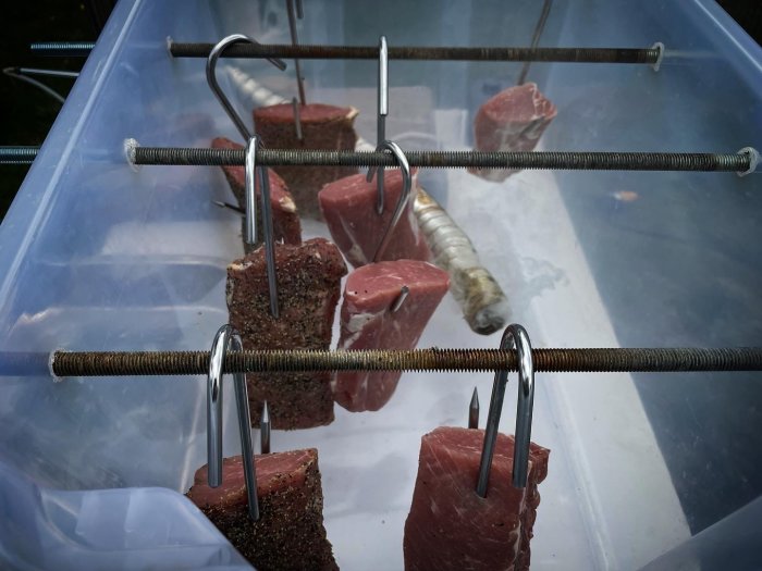 Köttbitar upphängda för rökning i hemmagjord rök.