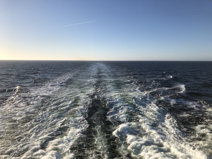Vaken bakom fartyg på öppet hav under klarblå himmel.
