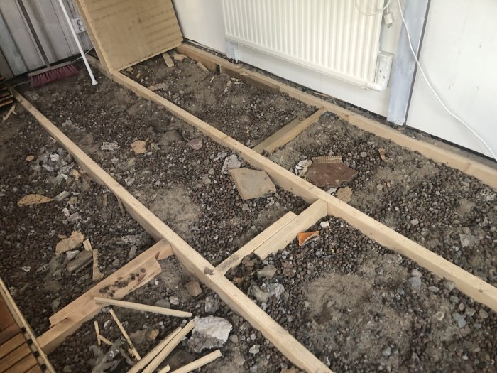 Grusunderlag med reglar och lecakulor i ett uterum förberett för betonggjutning.