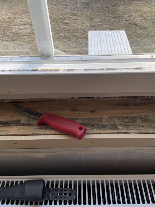 Bild på avlägsnad fönstersalning med svarta fläckar på träregeln och verktyg på fönsterbrädan.