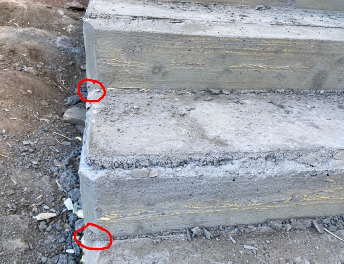 Betongtrappa med två steg där främmande material sticker ut vid de röda markeringarna.
