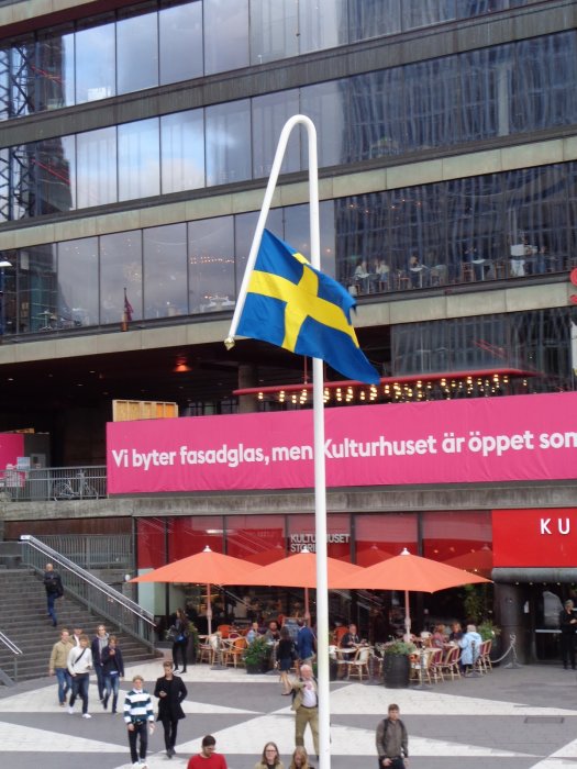 Svensk flagga framför byggnad med text "Vi byter fasadglas, men Kulturhuset är öppet som vanligt".