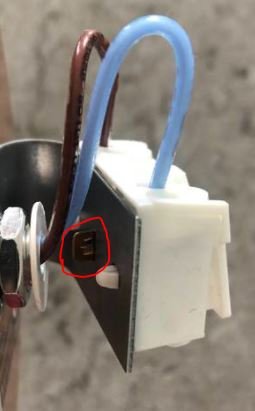 En elektrisk komponent med en utstickande flärp markerad med en röd cirkel.