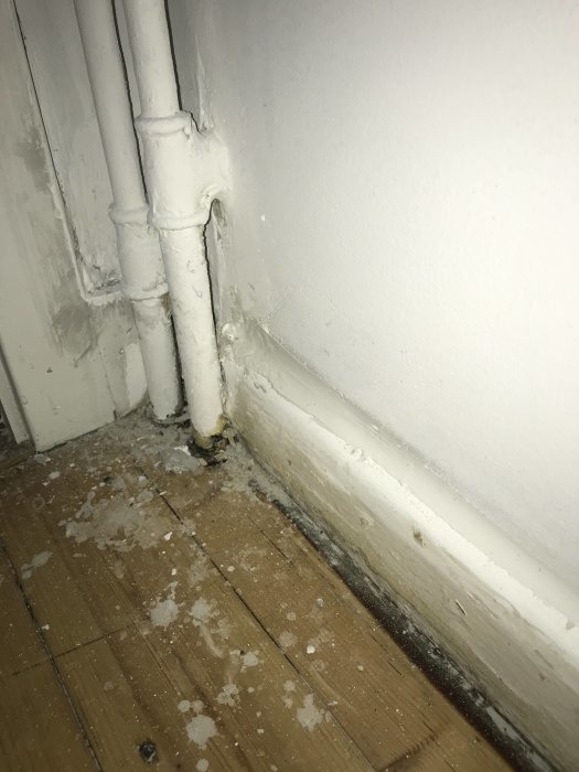 Ojämn och slarvig fogning kring rör och golvlist med synliga spackelrester.