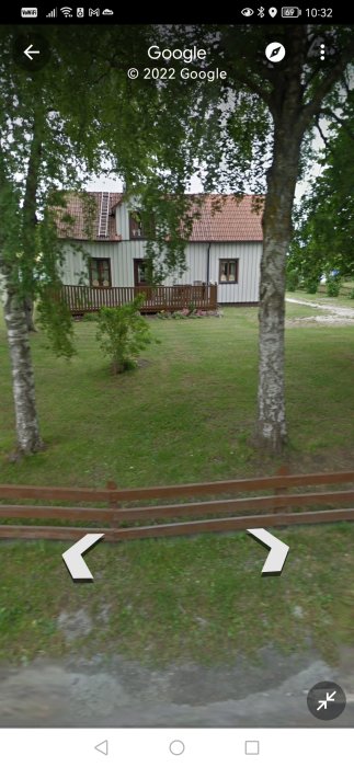 Trädgård med tvåvåningshus, träaltan och grönt gräs synligt genom Street View-interface.