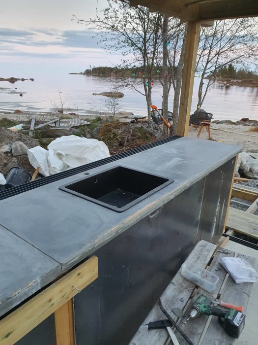 Nyinstallerad diskho i en gjuten köksbänk på en byggarbetsplats med havsutsikt i bakgrunden.