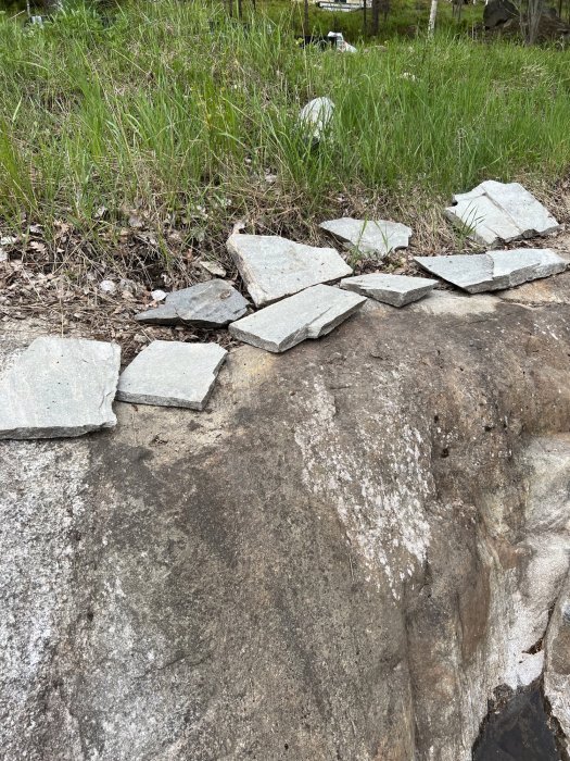 Ojämn bergstrappa med utspridda skifferplattor på sidan mot gräsmark.