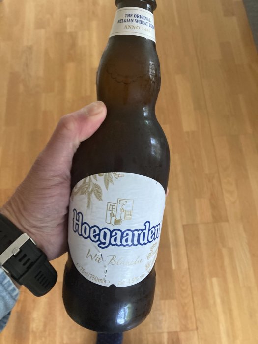 Hand håller en Hoegaarden ölflaska med texten "The Original Belgian Wheat Beer ANNO 1445".