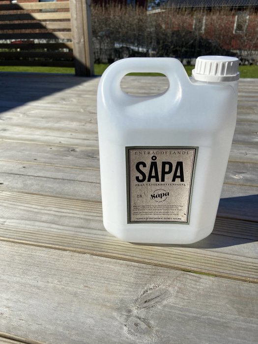 Såpaflaska på nysopt träaltan i soligt väder.