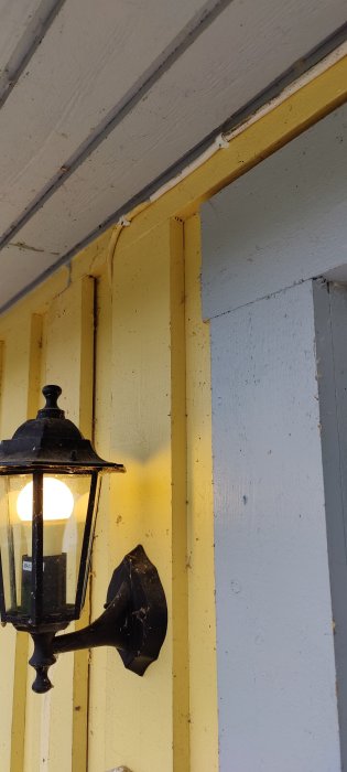 Vägglampa vid en husvägg där det saknas tydligt synliga friskluftsventiler, som belyser ett möjligt byggfel.