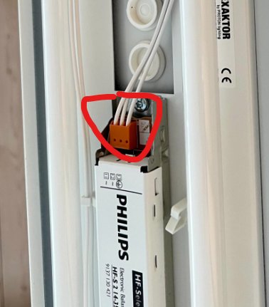 Vit elektrisk installation med en orange dosa och instuckna vita kablar, markerade med en röd cirkel.