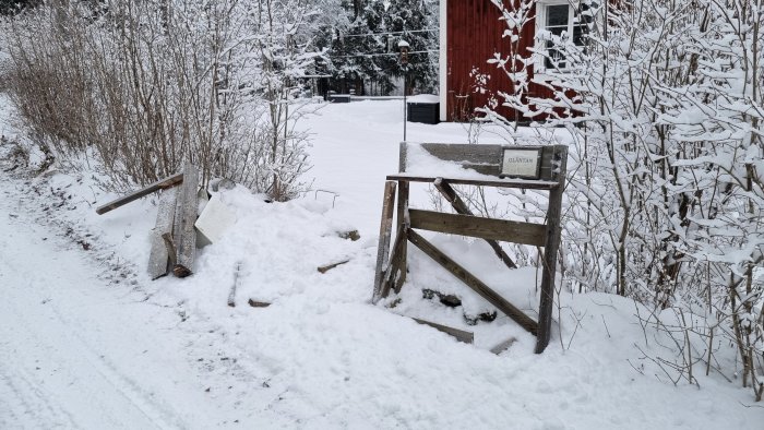 Snötyngd trätrappa utanför en röd stuga, täckt av vinterlandskap.