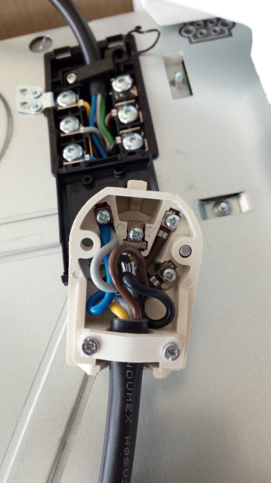 Eluttag med öppet fack där kablar med olika färger är anslutna till flera plintar.