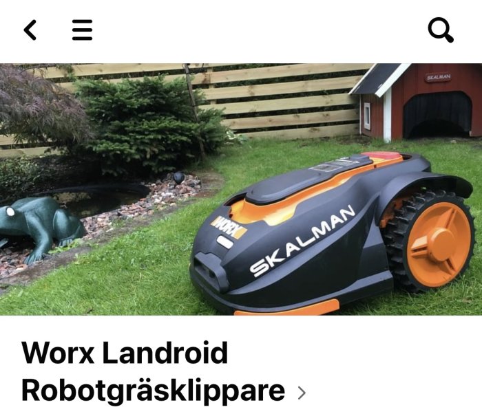 Worx Landroid robotgräsklippare med tydlig märkning "SKALMAN" parkerad på gräsmatta nära en damm.