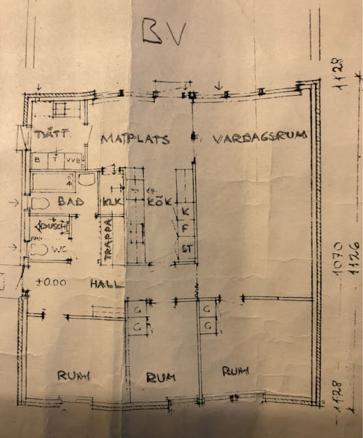 Handritad planritning av bottenvåningen i ett 1,5-planshus, med kök, vardagsrum och flera mindre rum.