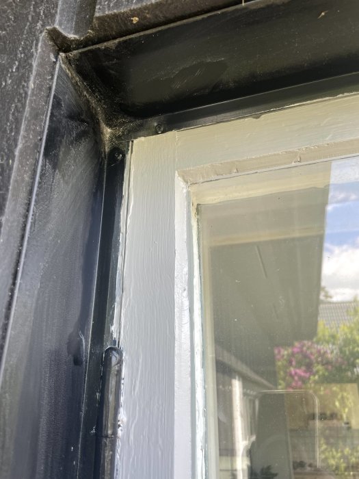 Närbild av nyligen renoverat fönster med ojämn omfogning och gamla träramar.