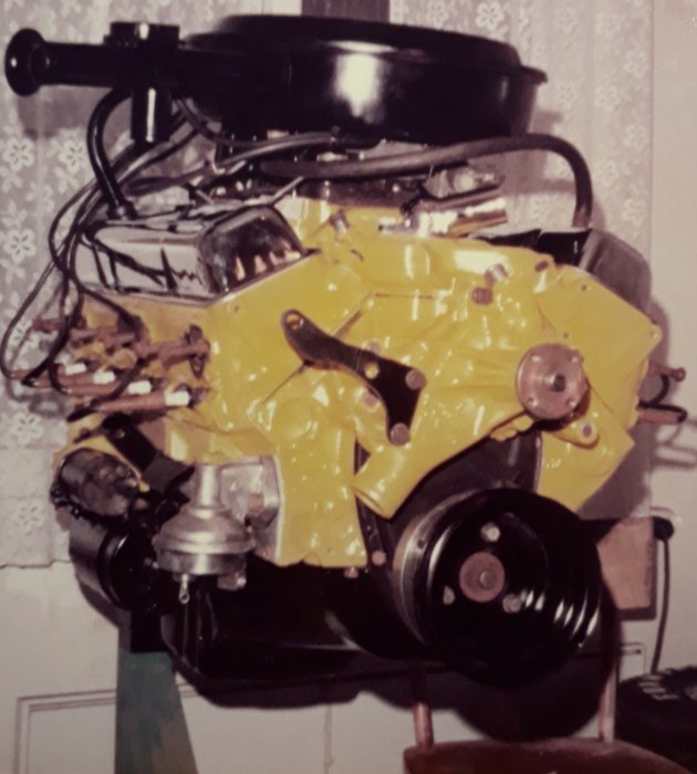 Gammal Chevelle 307 motor målad i gul färg från 80-talet med synliga blockpackningar och utrustad med en svart luftrenare.
