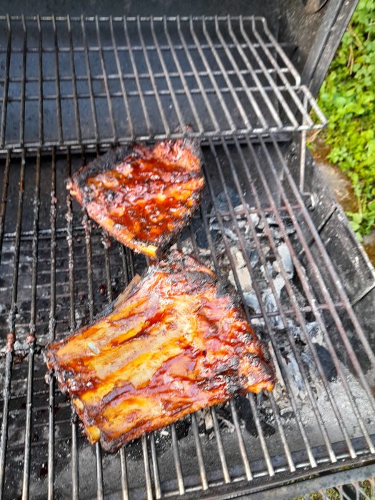 Grillade revben med glaserad yta på kolgrill nära slutfasen av tillagningen.