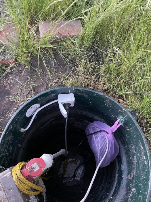 Elektrisk kabel och traf till gräsklippare i plastpåse för skydd mot väta i en inspektionsbrunn.