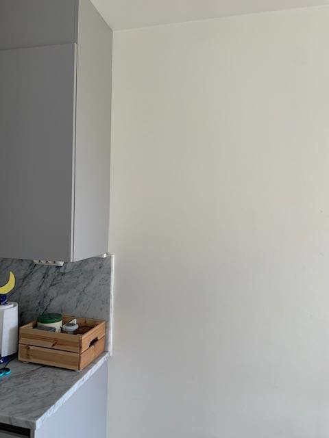Ojämn väggkant vid köksskåp och marmorskiva som sticker ut; osäkerhet om tapetsering.