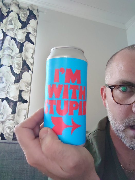 Man som håller en burk med texten "I'M WITH STUPID" och pekande pilar, med rosor i bakgrunden.