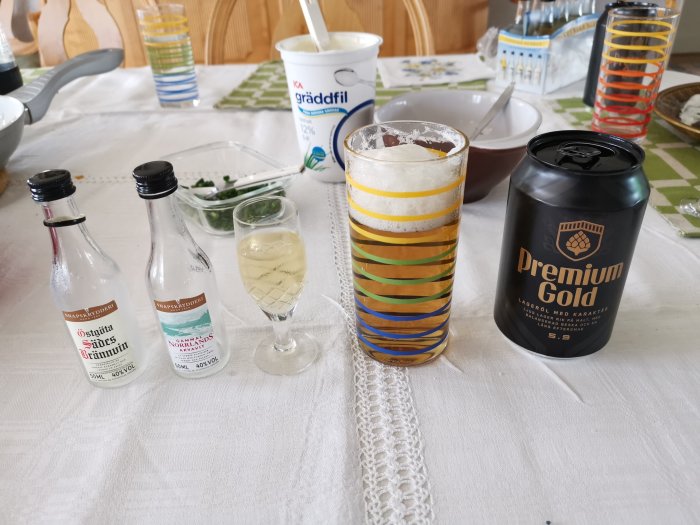 Dukat bord med småflaskor brännvin, ett glas, gräddfil och en ölburk märkt 'Premium Gold'.