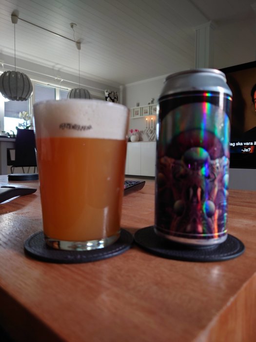 Ölglas fyllt med öl bredvid en burk med etikett på ett bord inomhus.
