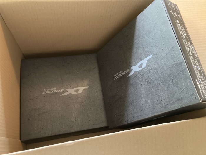 Två Shimano Deore XT cykelkomponentlådor i en kartong.