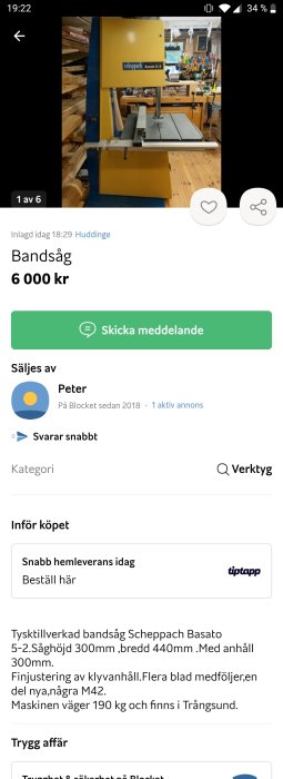 Gul bandsåg av märket Scheppach Basato 5-2 står i ett verkstadsutrymme med träverktyg och material i bakgrunden.