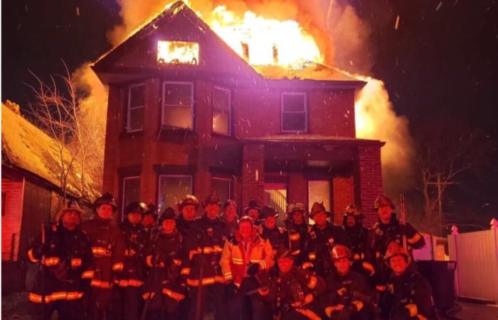 Brandmän framför brinnande hus på natten.