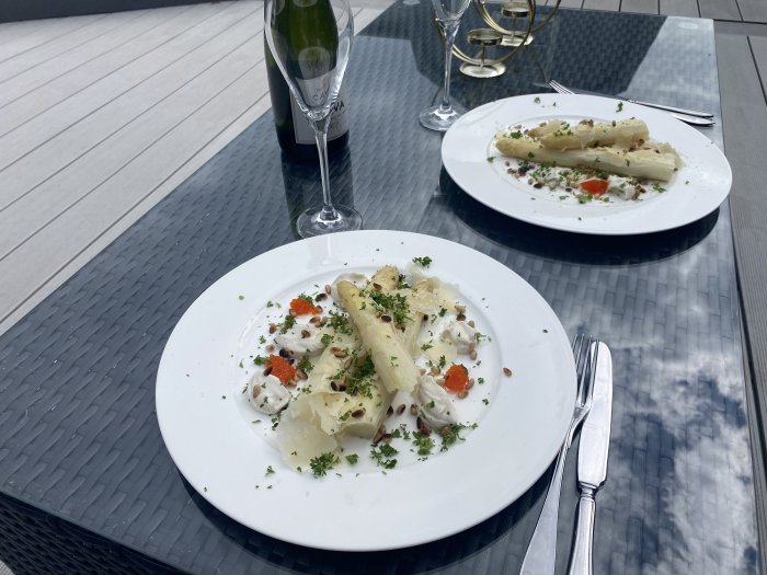 Två vita tallrikar med vegansk mat och ett glas bubbel på ett utebord för firande av Mors dag.