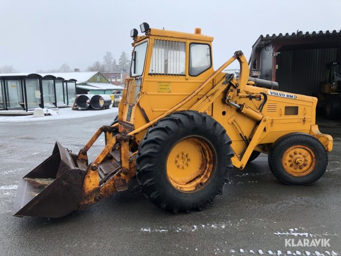 Gul hjullastare med skopa framför hytten parkerad på ett snötäckt underlag.