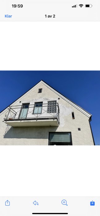 Gammal husfasad med skadad och flagande puts som behöver renoveras, blå himmel i bakgrunden.