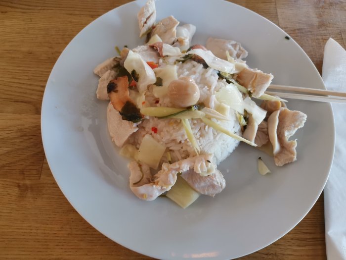 Tallrik med Tom Kha Gai, thailändsk kokossoppa med kyckling och ris, ätpinnar.