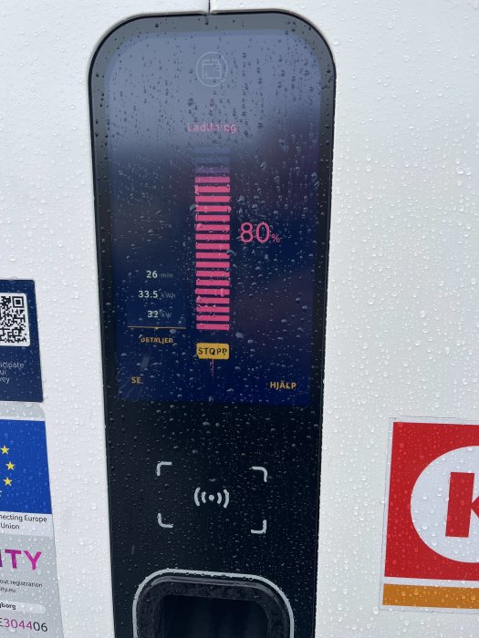 Laddstationsskärm visar 80% laddning med laddtiden 26 min och effekten 33.5 kW under regn.