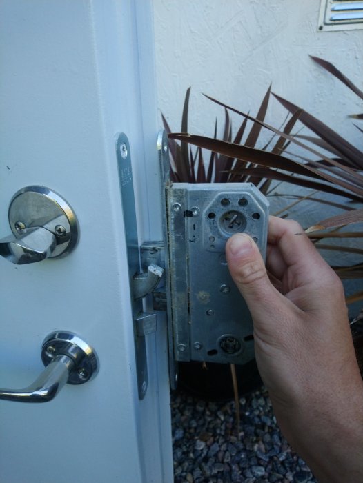 En person håller en gammal låskista vid en dörr, synliga assa evo 310 märkningar.