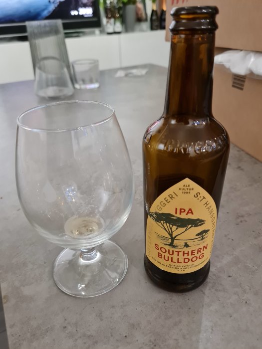 En tom ölglas och en nästan tom flaska IPA på en köksbänk.