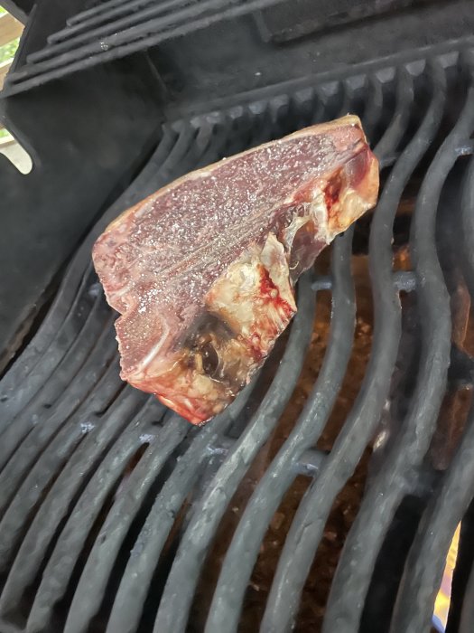 T-bone steak på en grill med galler, redo för en lyxig grillonsdag.