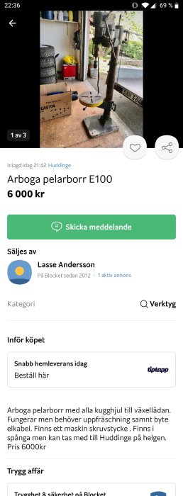 Arboga pelarborr E100 i ett garage, synlig slitage, med tillbehör och omgivande verktyg och föremål i bakgrunden.