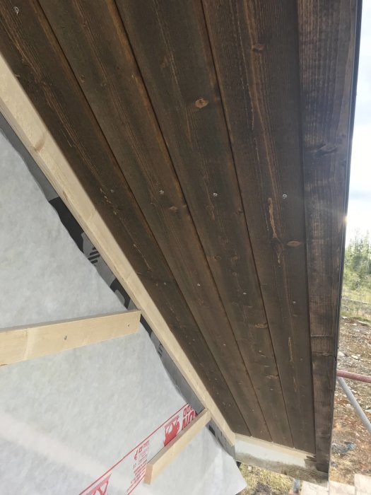 Väderskyddad byggkonstruktion med vindduk och spikläkt, och underspikning synlig.
